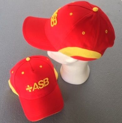 Zwei rote ASB-Basecaps mit gelben Details und gesticktem Logo, eine auf einem Modellkopf,…